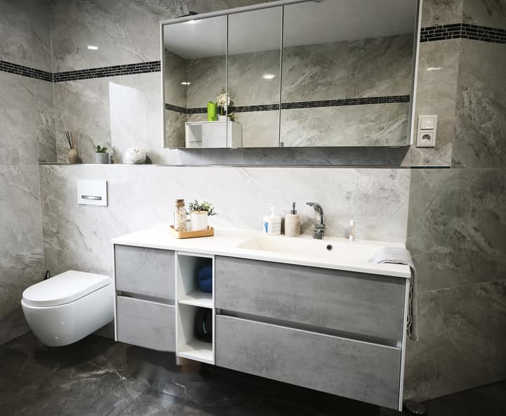 Neues Bad mit Waschtisch, Spiegelschrank, Wand-WC und großen Fliesen in Marmoroptik